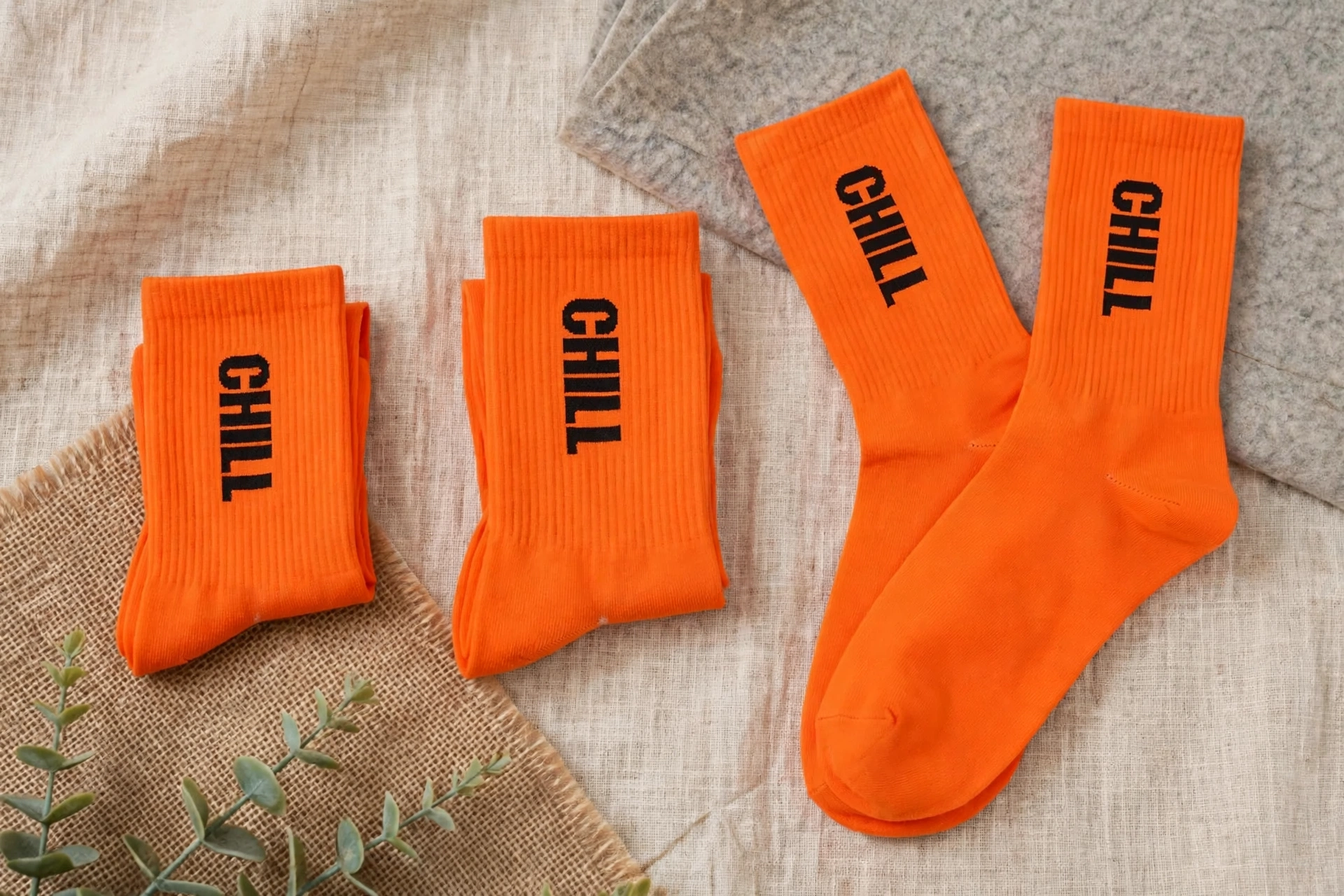 Bright orange CHILL crew socks with black vertical logo in three pairs showing Small Medium Large flexible sizing - universal sizing simplicity inventory management